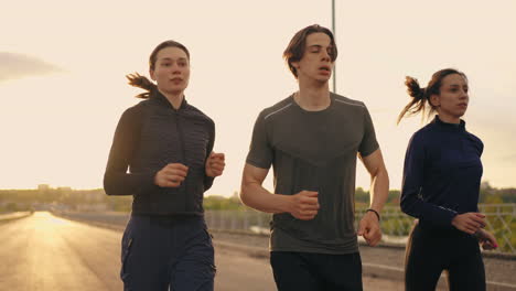 three-friends-are-training-outdoors-in-summer-two-women-and-man-are-running-in-open-air